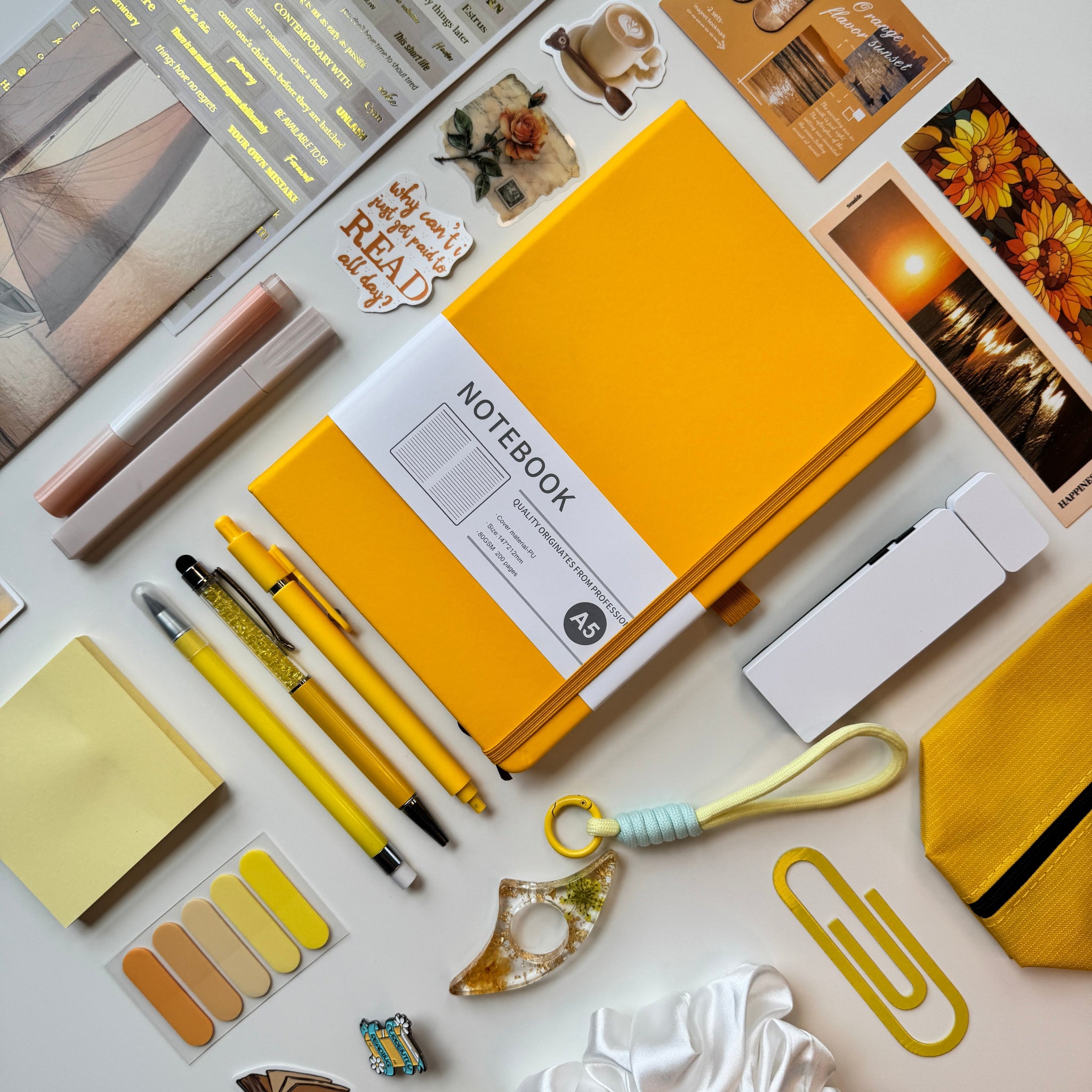 Yellow notebook surrounded by stationery items on a light surface