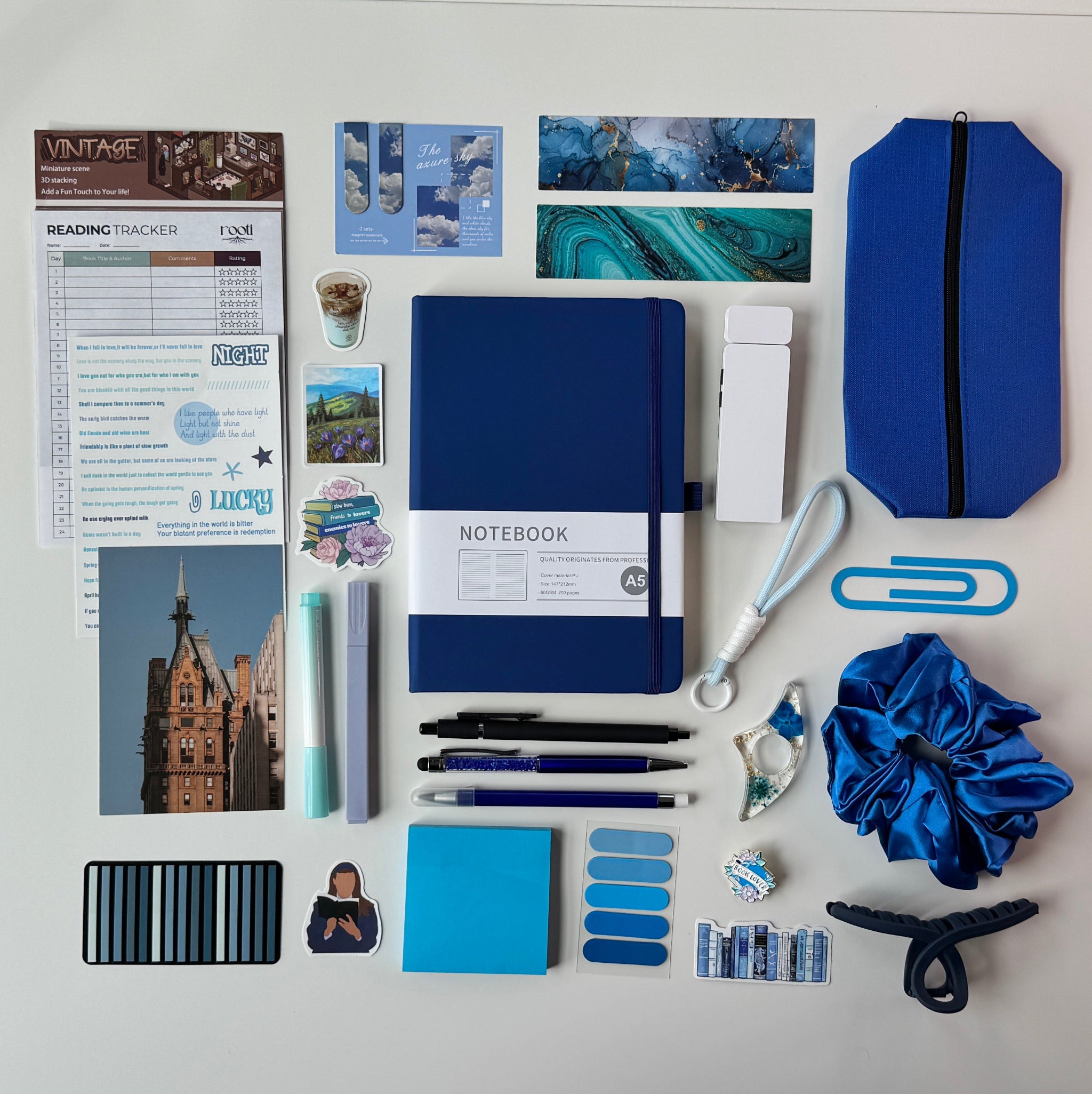 Desk with stationery items including notebooks, pens, and paperclips on a white surface.