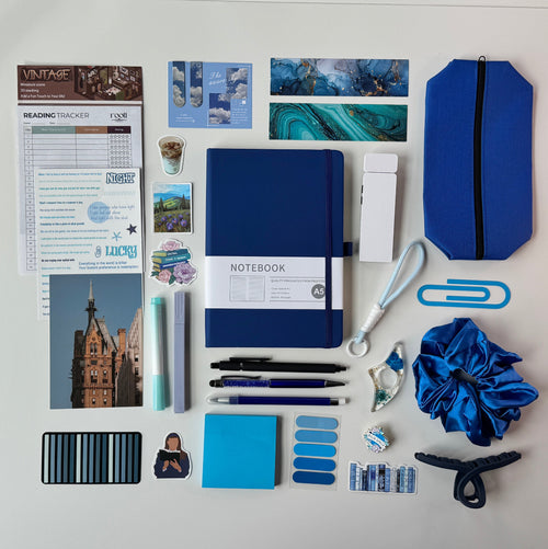 Desk with stationery items including notebooks, pens, and paperclips on a white surface.